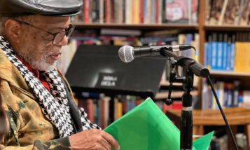 older man reading at a microphone